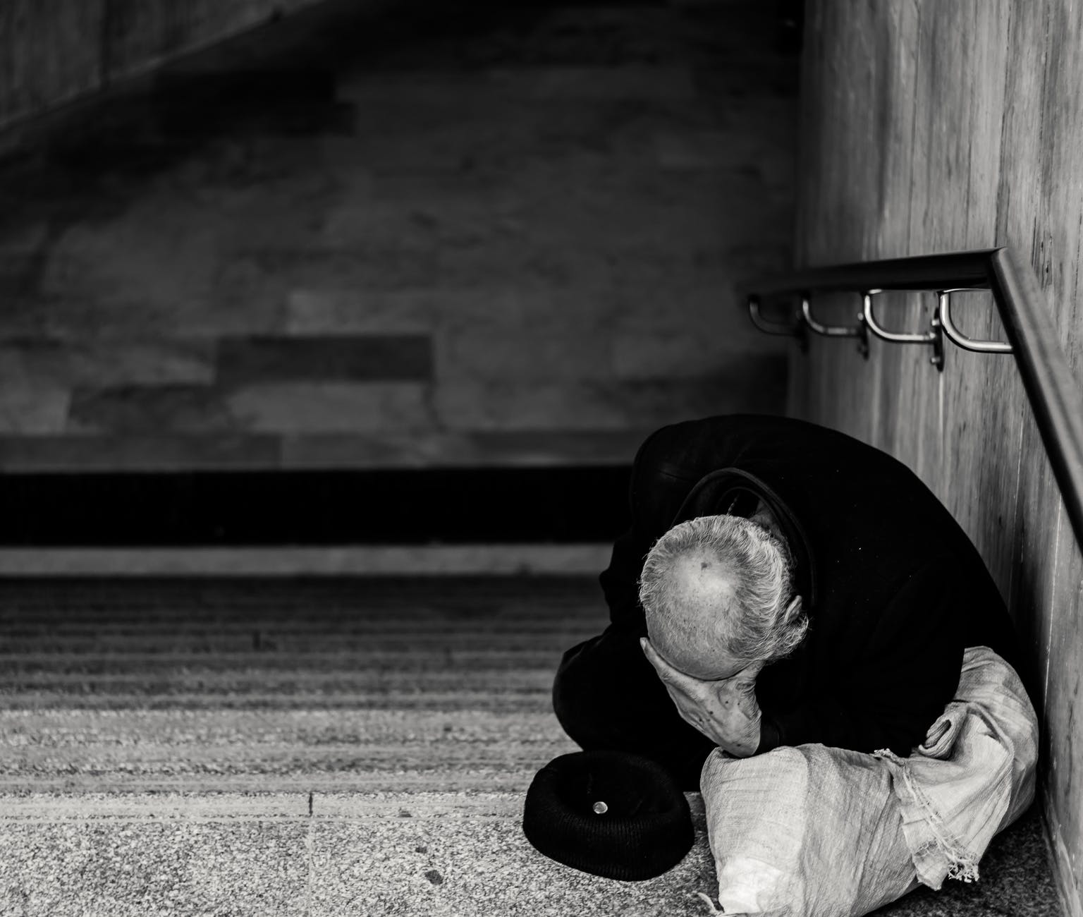 monochrome photography of man sitting on staircase